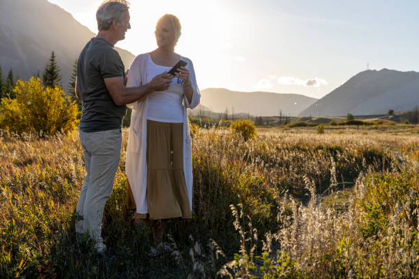 istock Mature couple use mobile phone in mountain meadow 2177466791