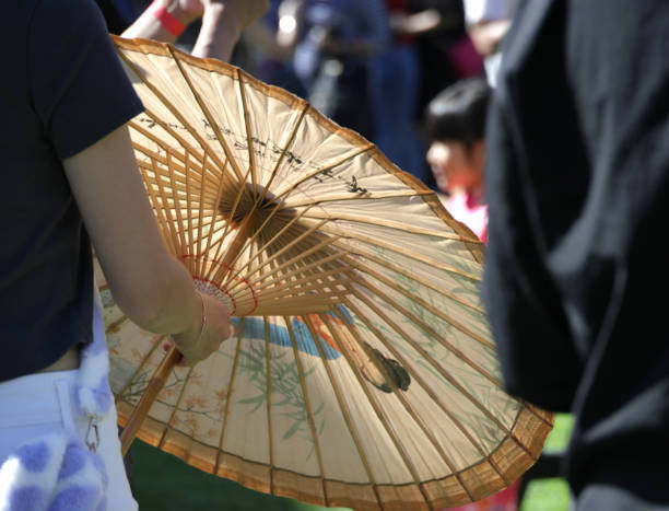 A young festival attendee lowers her parasol displaying an illustration of a Chinese woman on the panels.
