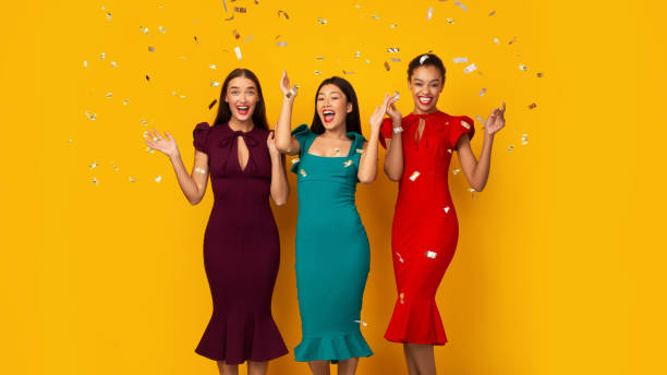 istock Three Party Girls Standing Under Falling Silver Confetti, Yellow Background 2177474809