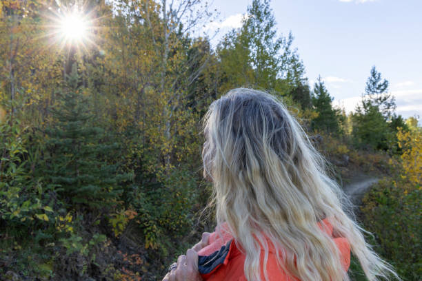 Profile view of mature woman walking along mountain pathway in autumn, Crowsnest Pass, Alberta