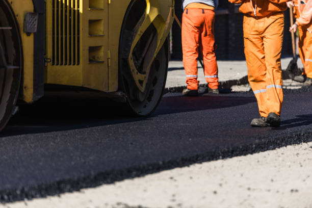 istock Construction workers in orange uniforms paving a road with an asphalt roller on a sunny day 2177480419