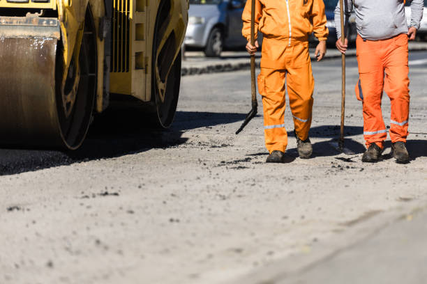 istock Construction workers in orange uniforms walking beside a steamroller on a road construction site on a sunny day 2177480425