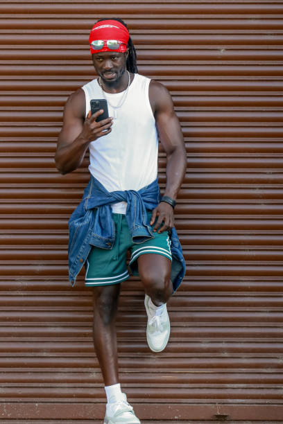 istock young afro man using mobile phone on the street with red scarf on his head, copy-space 2177482247