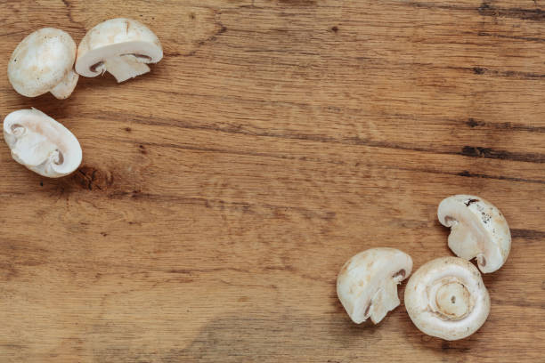 Vegetarian food. Fresh white mushrooms champigonons on wooden kitchen table as background.
