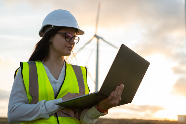 istock Caucasian female technician working outdoors in the wind turbines field with laptop. 2177489322