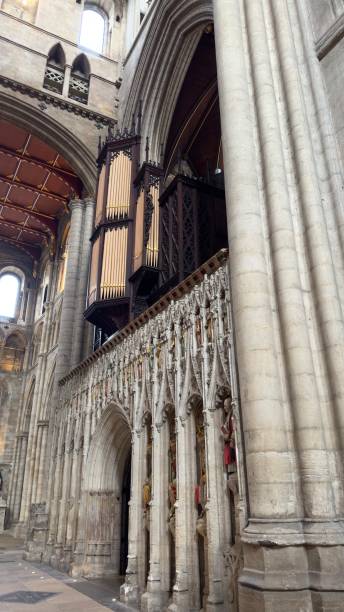 A stunning view of a cathedral interior showcasing intricate stone carvings, tall columns, and a large organ positioned above. The architectural details highlight the grandeur and historical significance of the structure.