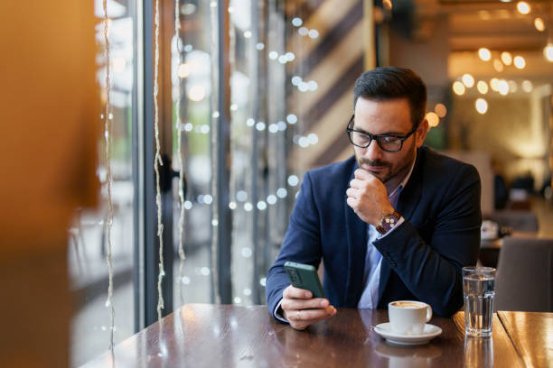 istock Focused Businessman Engaged with Smartphone in Cafe Setting 2177490479