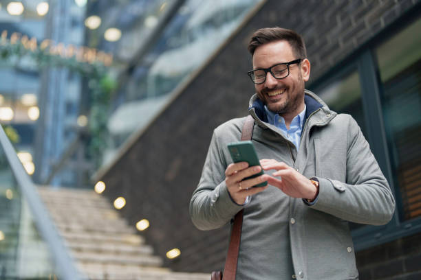 istock Smiling Businessman Engaging with Smartphone Outside 2177490681
