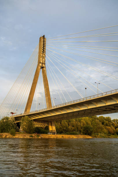 istock A suspension bridge with cables stretching across a river under a clear sky. The bridge stands tall, reflecting golden light 2177491692