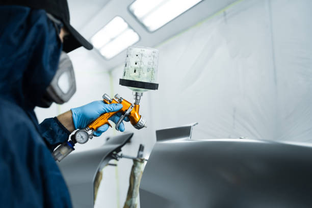 istock Putting lacquer on metal to give surface smooth appearance. Worker wearing protective mask and gloves is applying lacquer on car using LVLP spray gun. 2177496654