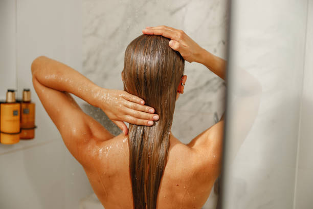 A Woman Enjoying a Refreshing Shower While Using Various Hair Care Products in a Modern Bathroom