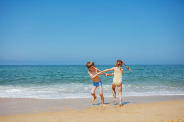 Siblings playing sand castle by the sea