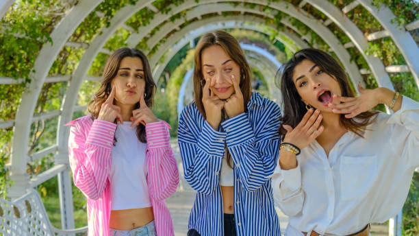 Friends in a park, looking at the camera while making funny facial expressions
