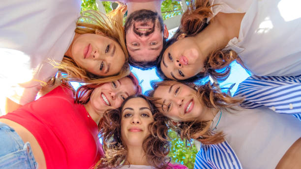 istock A large group of friends gathered together, forming a circle while smiling and looking down at the camera, having fun 2177509822