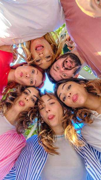 istock A large group of friends gathered together, forming a circle while smiling and looking down at the camera, having fun 2177509847