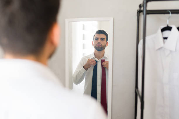 istock Young professional choosing between two ties as he prepares for work in the morning 2177511221