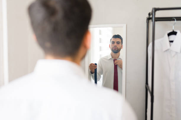 istock Hispanic businessman fixing his tie while preparing for the day in a spacious closet 2177511248
