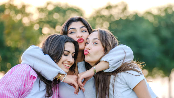 istock Three beautiful young  women posing for the camera on a sunny day in a tree-filled park 2177515552