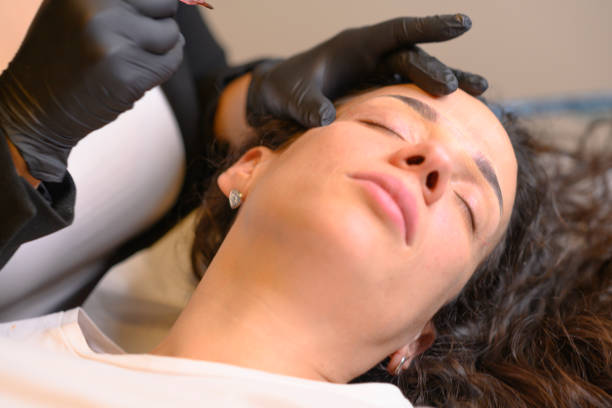 istock Beautician applying permanent eyebrow makeup with microblading machine on brunette hispanic 30 woman 2177517459