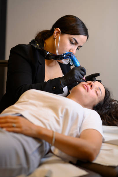 istock Beautician applying permanent eyebrow makeup with microblading machine on brunette hispanic 30 woman 2177517466