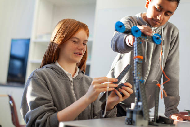 istock Teenage girl in high school classroom making physics construction science engineering technology mathematics STEM project with Asian classmate 2177523311