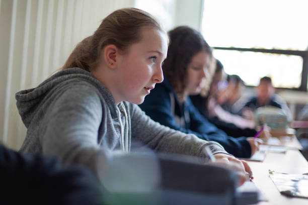 istock Elementary school junior high student girl listens to teacher in classroom 2177523340