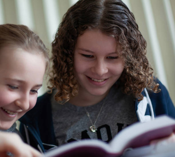 istock Two girls elementary school students reading book in classroom library together 2177523465