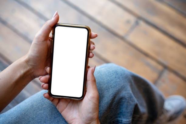 istock A woman's hand holding a smartphone with a white screen mockup while sitting on a terrace. 2177525695
