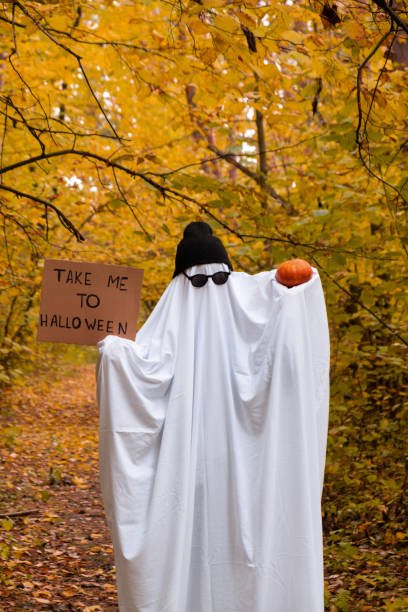 istock Trendy halloween celebration outdoors in autumn time. Handmade ghost costume from sheets, cap and glasses. Fall forest 2177533625