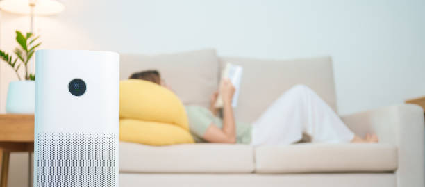 istock Air Purifier with woman read and relax on sofa. Purification system for filter and cleaning dust PM2.5 HEPA and virus in home. Allergy, Pure air, health lifestyle, Wellness life and Air Pollution 2177533841