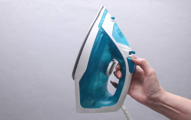 istock Female hand holding an iron for ironing on a gray background 2177535853
