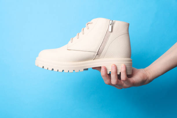 istock Female hand holding a white leather boot on a blue background 2177536121