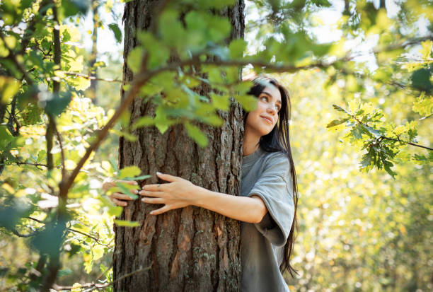 istock Young woman embracing a tree while enjoying nature in a sunlit forest during summer 2177537416