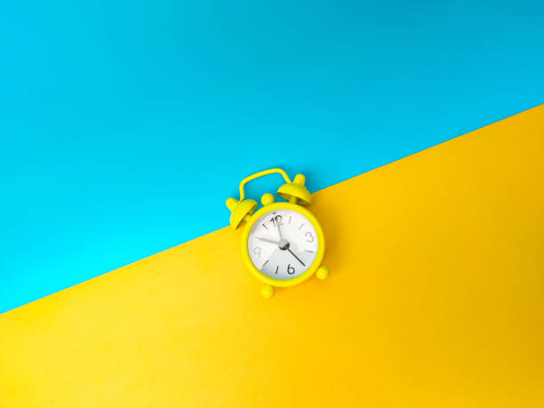 istock Top view yellow alarm clock on a yellow and blue background. 2177539254