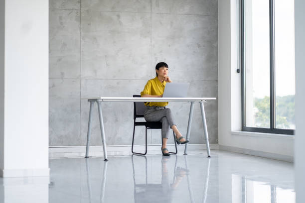 Woman at modern desk, focused on work in bright minimalist office space