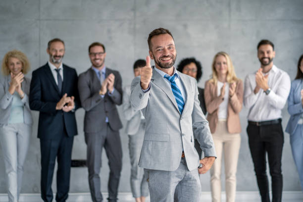 istock Happy businessman giving thumbs up with supportive team applauding. 2177550188