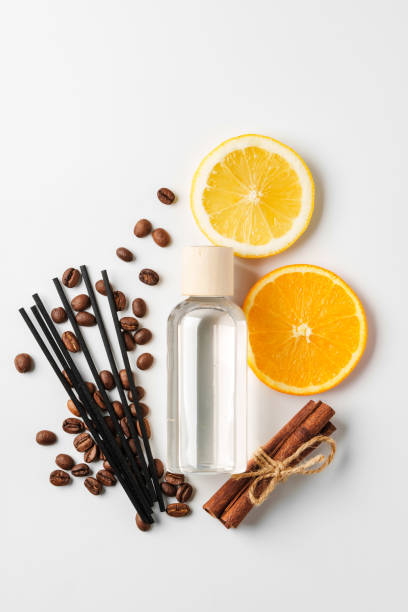 Aromatic display of citrus fruits, coffee beans, cinnamon sticks, and diffuser on a clean white surface
