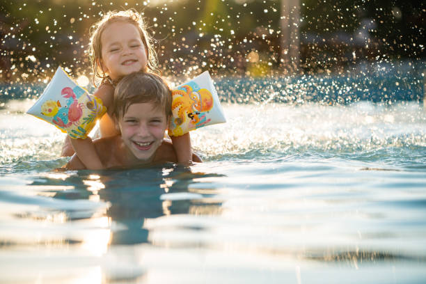 istock Brother and sister playing in swimming pool 2177555021