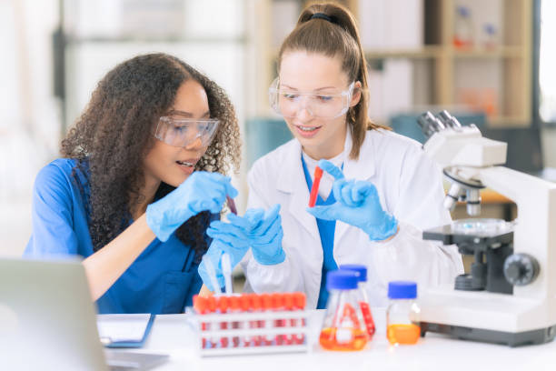 istock Two female scientists work in a laboratory with blood samples and test tubes filled with solution with pipettes from droppers while conducting research. 2177556250