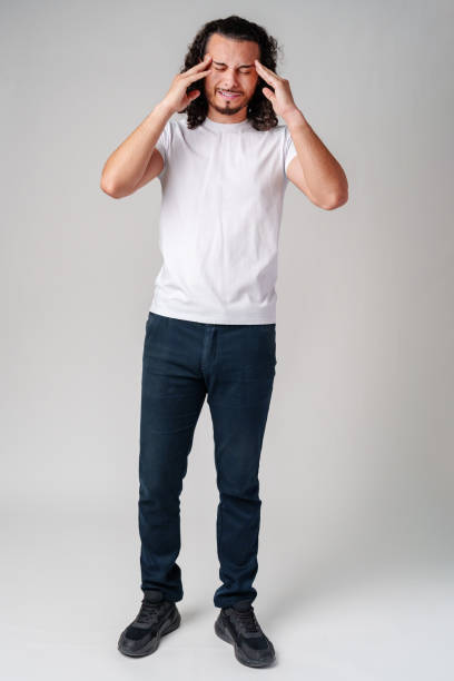 istock A young man with curly hair rubs his forehead in a casual indoor setting while expressing frustration 2177556439