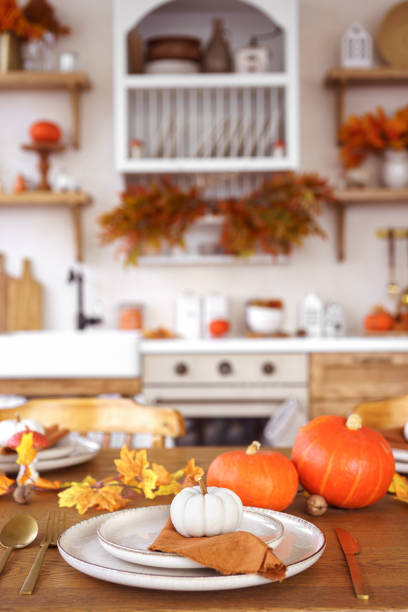 istock Dinning table setting for fall dinner, with pumpkins, leaves, and candle on kitchen background 2177561019