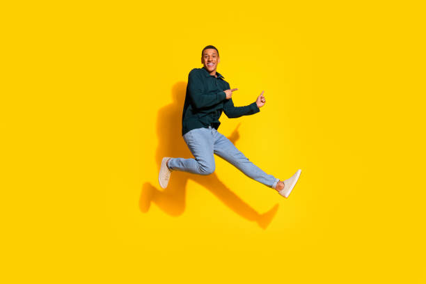 istock Full size photo of handsome young guy jump run point empty space dressed stylish green garment isolated on yellow color background 2177569177