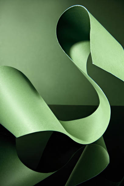 istock Against a deep green backdrop, a green paper ribbon twists and flows into an enticing S-shape, leaving a gap that may be used for display text and items. 2177571348