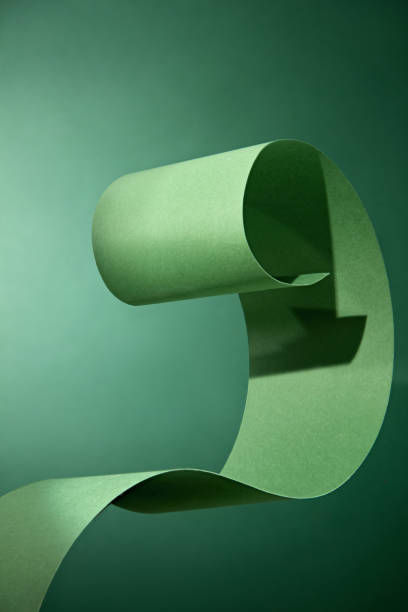 The image captures the green ribbon's smooth texture and delicate curves flowing against a deep green background. Creating space for display products or text.