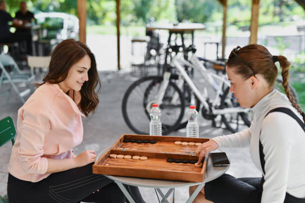 istock Two Beautiful Sisters Bonding Over Game of Backgammon While Taking Break From Bicycle Ride 2177573883