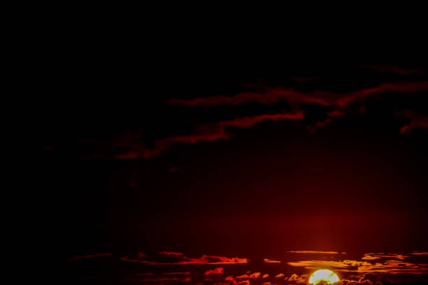 A sunset with a red sun in the sky. The sky is dark and the sun is the only light source