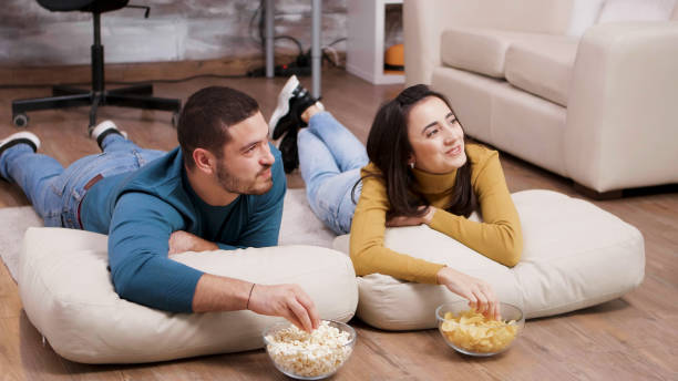 istock Young woman smiling at his boyfriend while watching tv 2177583452