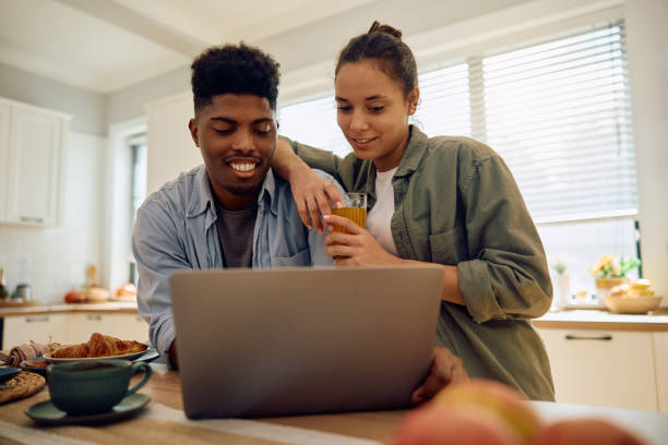istock Smiling multiracial couple using laptop in the kitchen. 2177584468