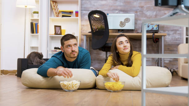 istock Cheerful couple watching tv sitting on pillows 2177584588