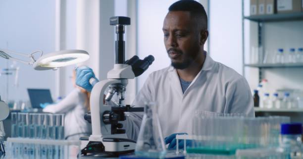 istock African American scientist looks under microscope, studies samples of new drug 2177591165
